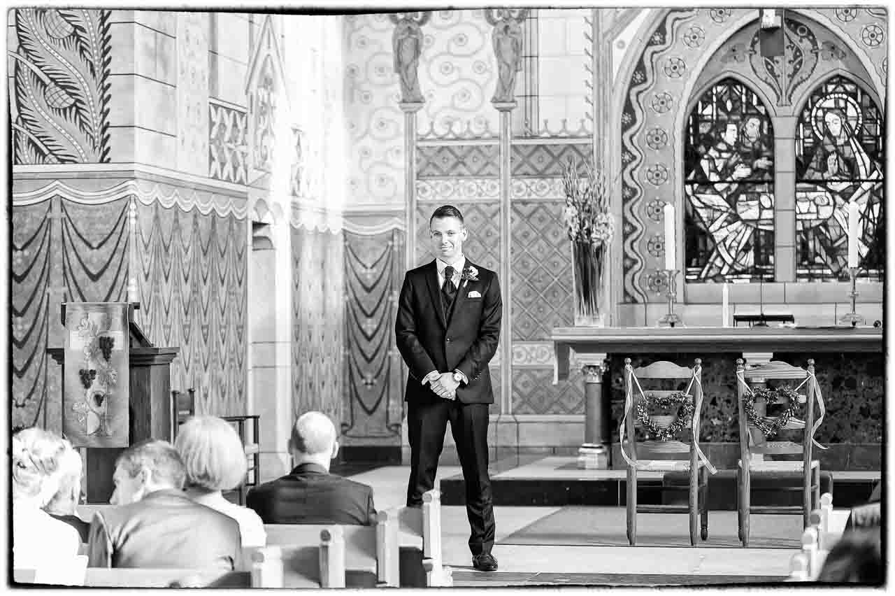 Stilvoller Braeutigam erwartet seine Braut in der Kirche. Die schoene Kirchenarchitektur und die festliche Atmosphaere versprechen einen besonderen Tag.