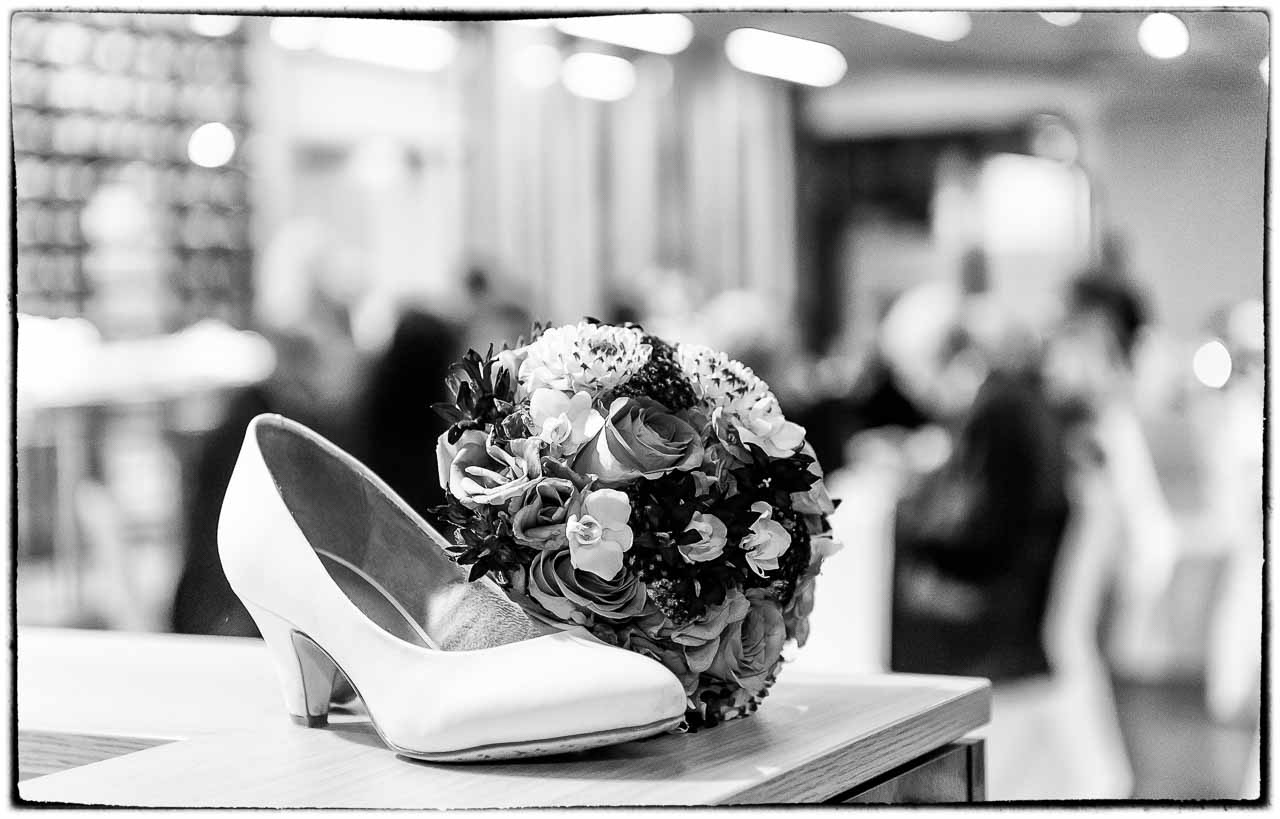 Elegantes Arrangement: Ein weisser Brautschuh und ein zarter Brautstrauss, kunstvoll arrangiert. Eine Erinnerung an den schoenen Tag im Standesamt.