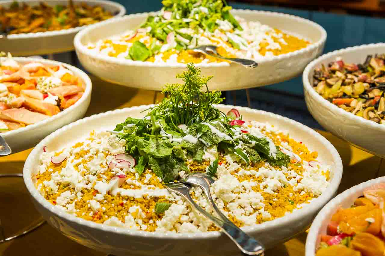 Einladendes Buffet mit koestlichen Salaten und raffinierten Speisen, praesentiert auf eleganten Schalen. Die Vielfalt und Frische laden zum Geniessen ein.