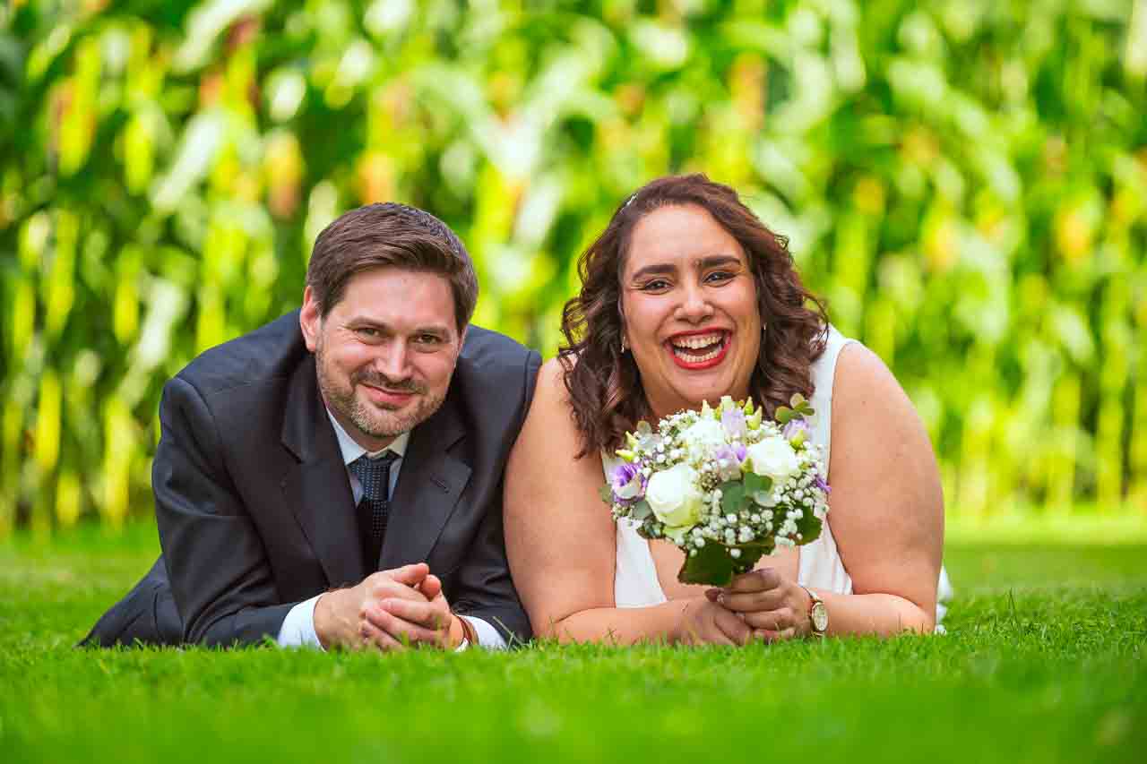 Strahlendes Brautpaar in Göttingen! Sie mit Brautstrauß, er im Anzug, glücklich im Grünen. Romantische Hochzeit, unvergessliche Momente.