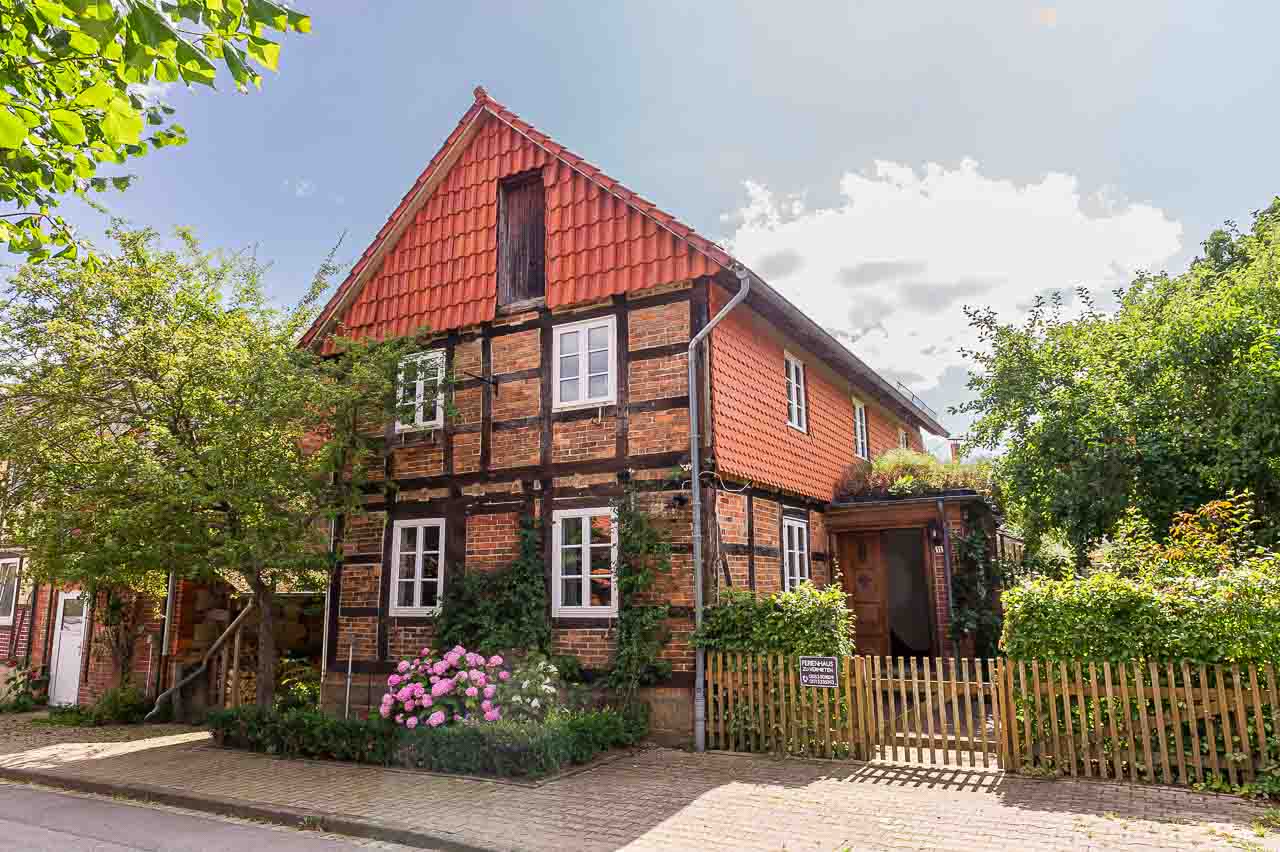 Fachwerkhaus in Ockensen mit roten Ziegeln und blühenden Hortensien. Ein charmantes Detail ländlicher Architektur.