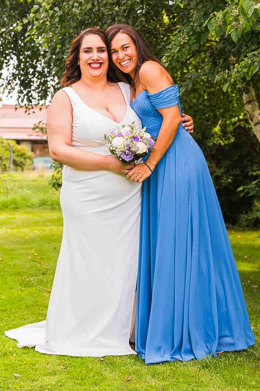 Braut mit Brautjungfer in festlichen Kleidern. Glückliche Momente im Grünen, ein unvergesslicher Tag. Elegante Hochzeitsfeier.