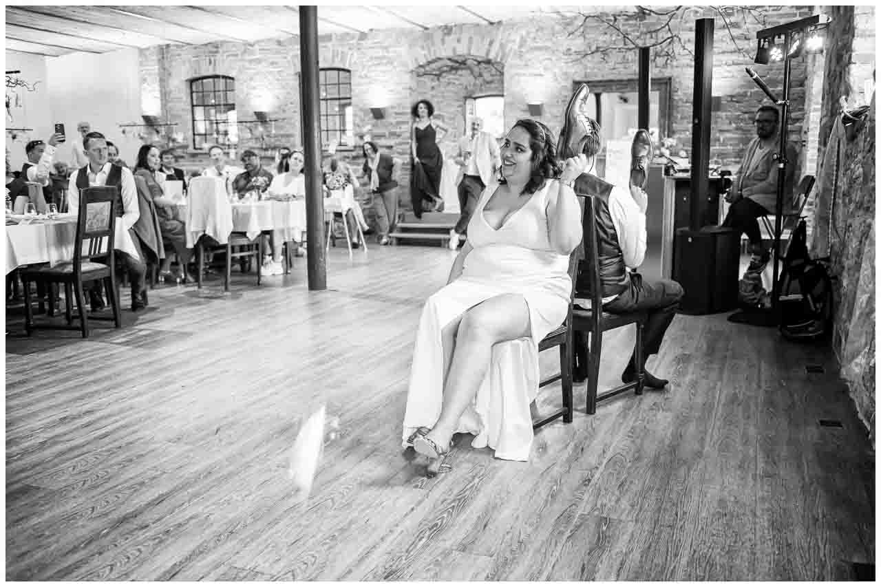 Brautpaar-Spiel in historischer Location: Sie im eleganten Kleid, er mit Schuhen in der Hand. Festliche Hochzeitsatmosphäre.