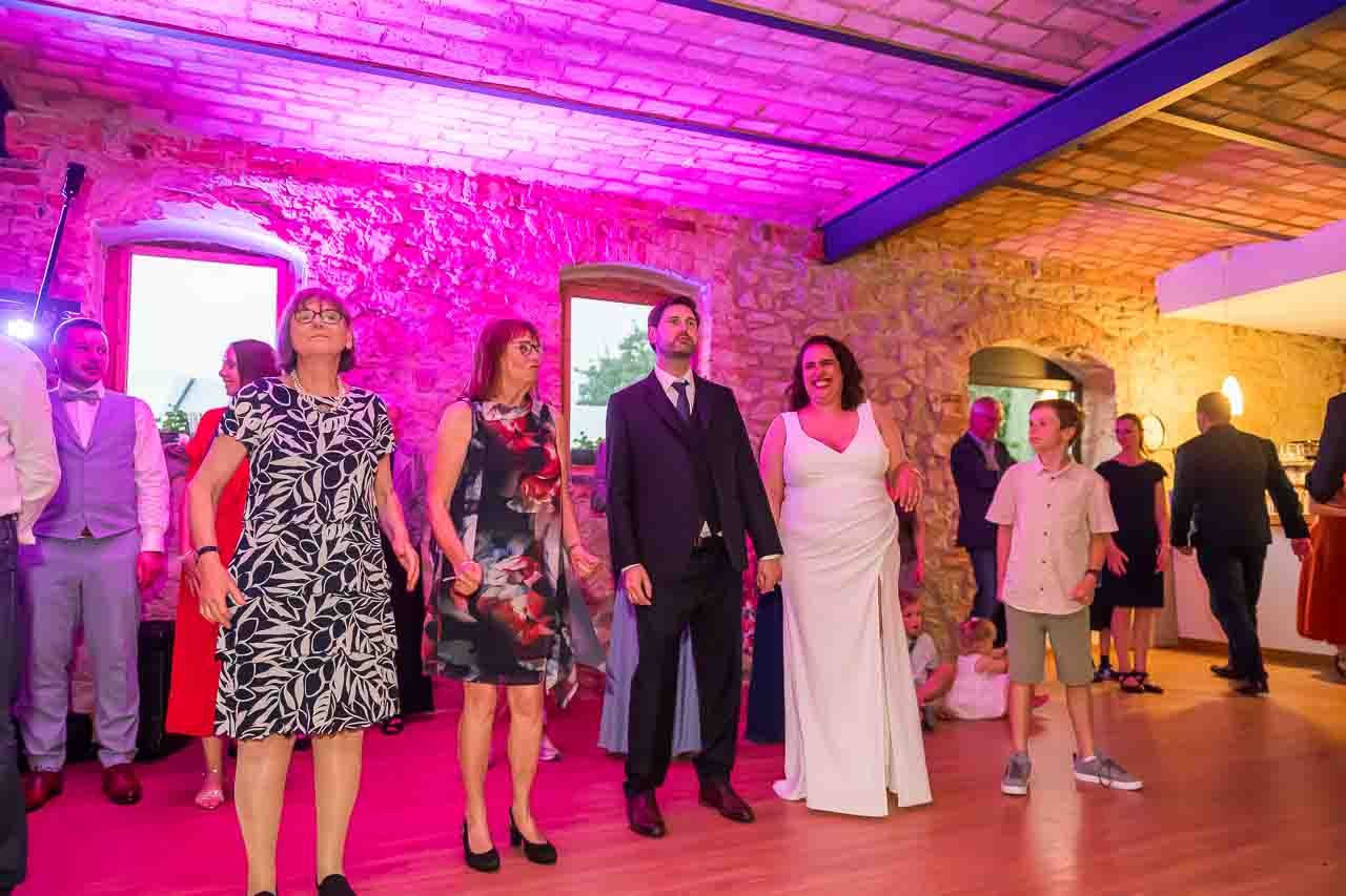 Hochzeitsfeier in historischer Location: Brautpaar tanzt mit Gästen. Elegante Kleider, festliche Stimmung. Unvergessliche Momente.