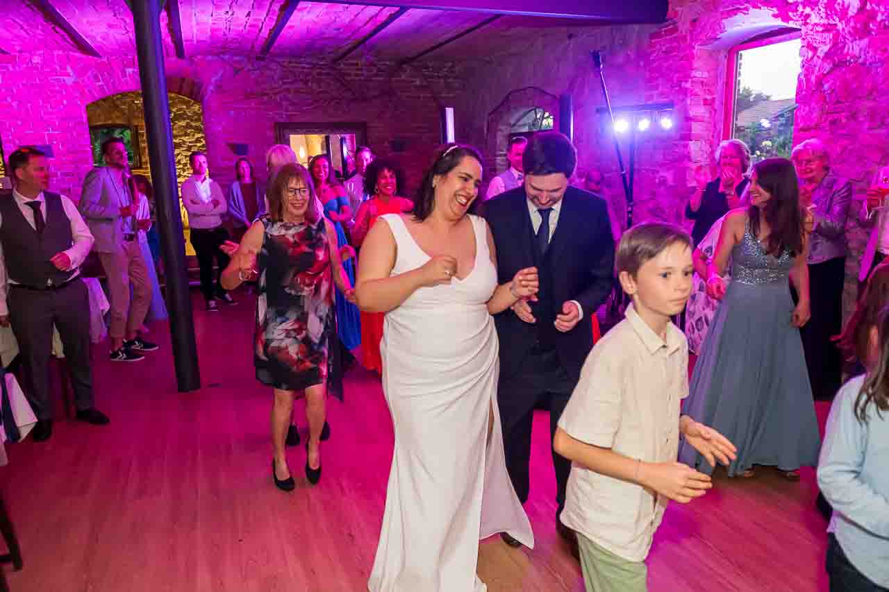 Hochzeitsfeier: Brautpaar tanzt ausgelassen im festlichen Saal. Fröhliche Gäste feiern die Liebe mit Musik und Tanz. Unvergessliche Momente.