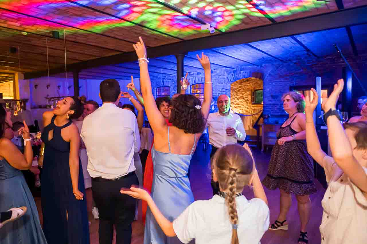 Tanzende Menschen feiern ausgelassen in Hannover. Bunte Lichter sorgen für eine fröhliche Atmosphäre. Festliche Kleider im Fokus.