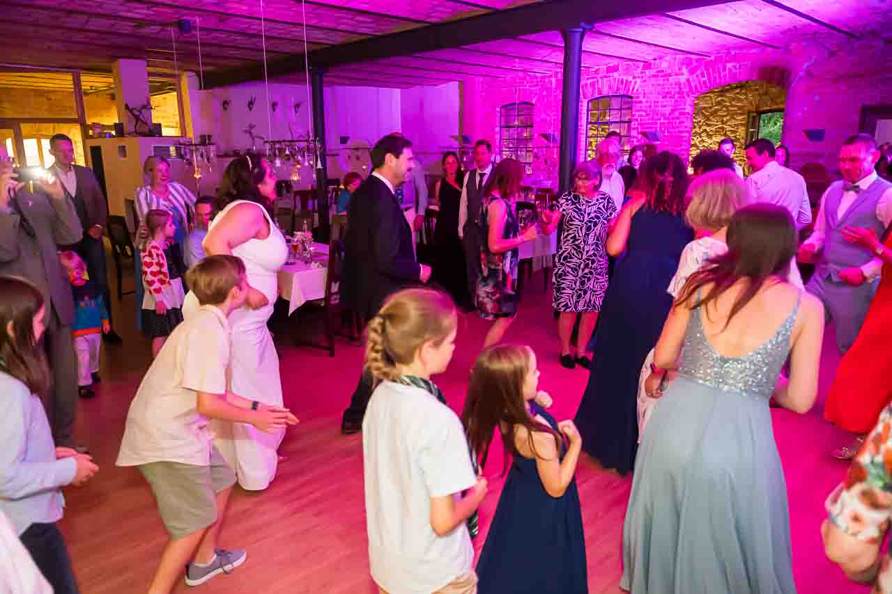 Fröhliche Hochzeitsgäste tanzen ausgelassen auf der Tanzfläche, umgeben von festlicher Beleuchtung und stilvoller Dekoration.