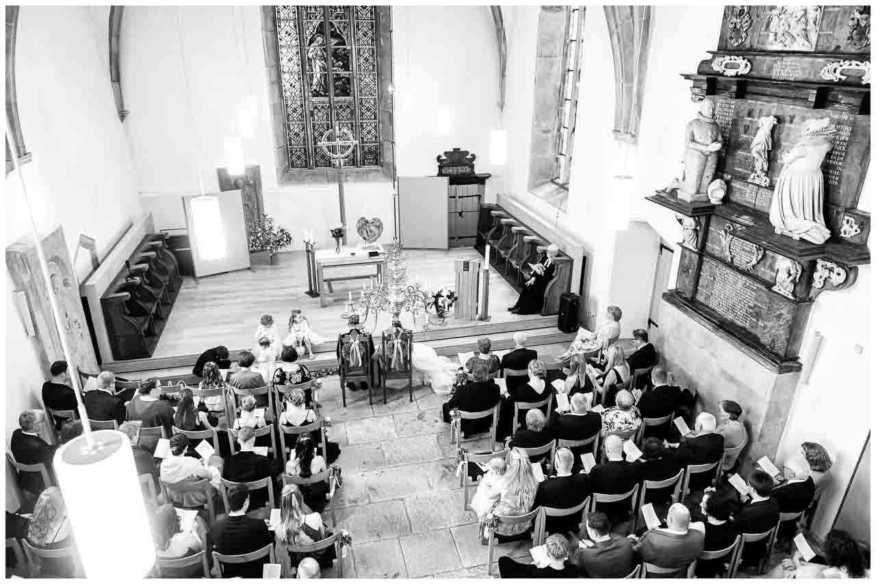 Hochzeitszeremonie in der Kirche: Brautpaar und Gaeste in festlicher Atmosphaere. Elegante Dekorationen und feierliche Stimmung. Liebe liegt in der Luft.