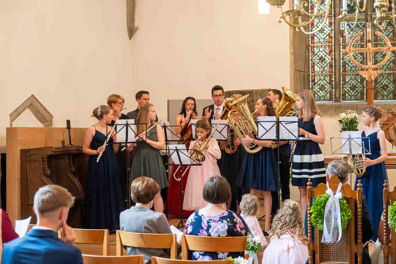 Musik zur Hochzeit in der Kirche: Ein Ensemble aus jungen Musikern spielt feierlich auf Floeten, Posaunen und Tubas fuer das Brautpaar.