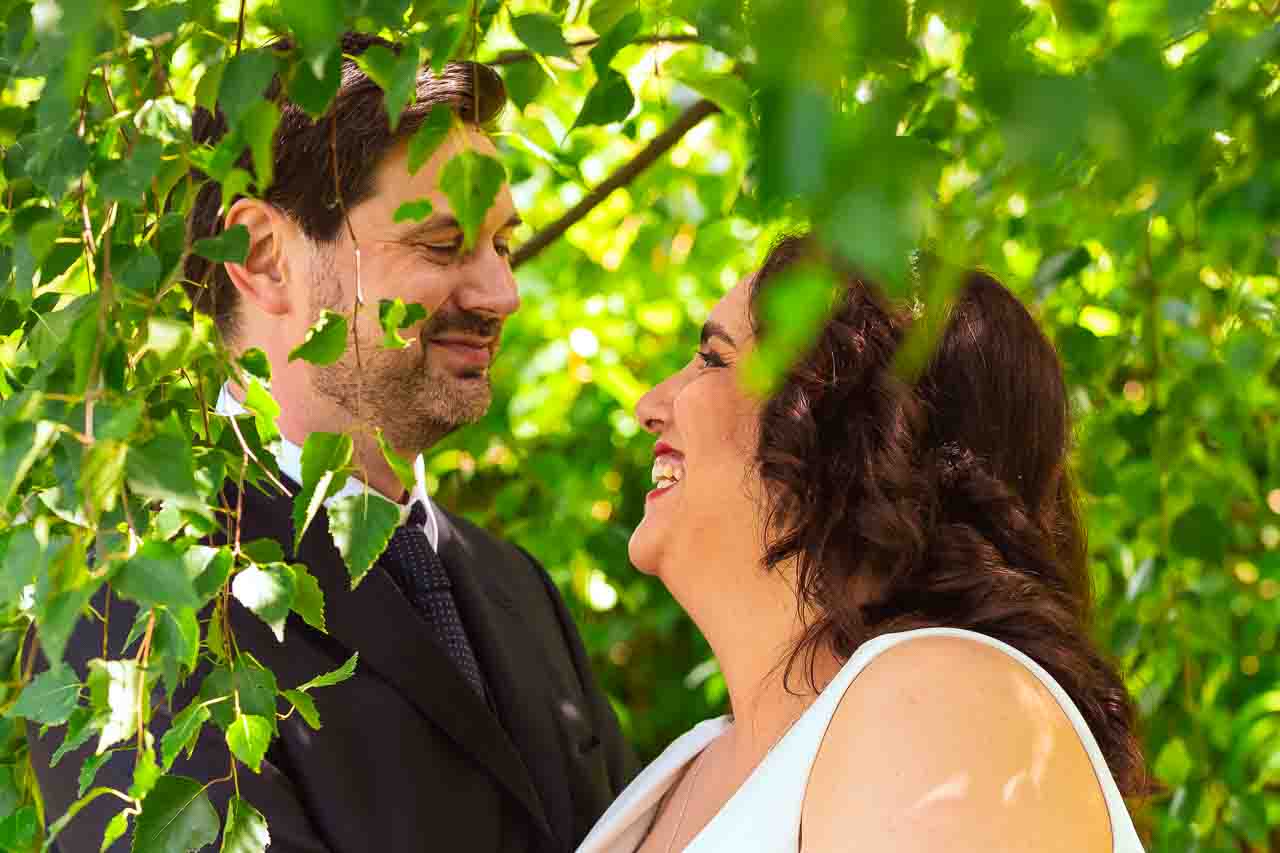 Romantische Hochzeit in Ockensen: Glückliches Brautpaar unter grünem Blätterdach. Liebevoller Blickwechsel, unvergessliche Momente im Grünen.