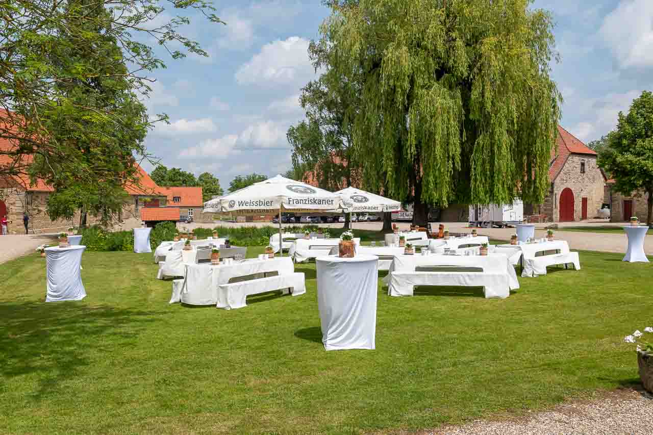 Idyllische Hochzeitsfeier im Schlossgarten: Festlich gedeckte Tische und Sonnenschirme auf gruener Wiese. Perfekt fuer unvergessliche Momente.