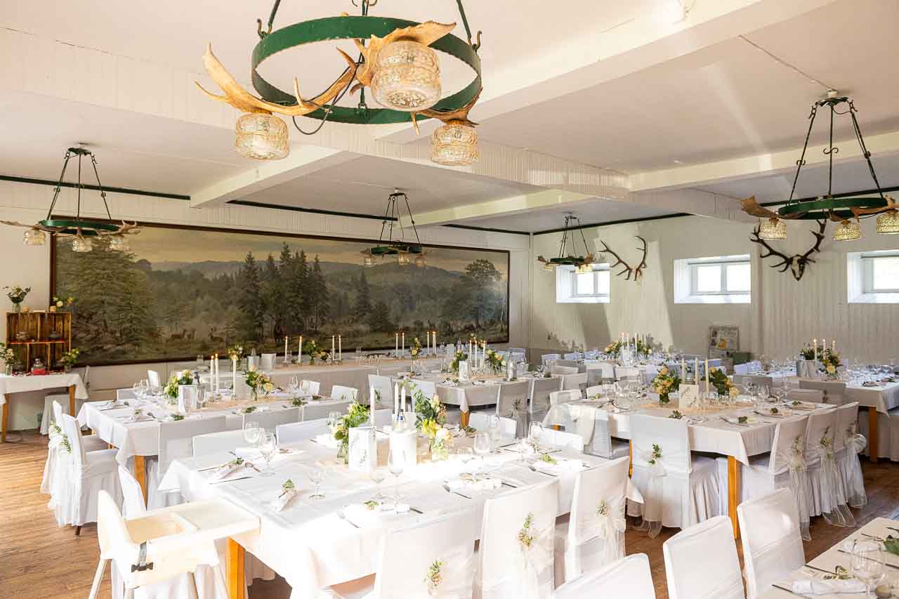 Festlich gedeckte Hochzeitstafel in einem eleganten Saal mit Hirschgeweih-Luestern. Romantische Dekoration fuer eine unvergessliche Feier.