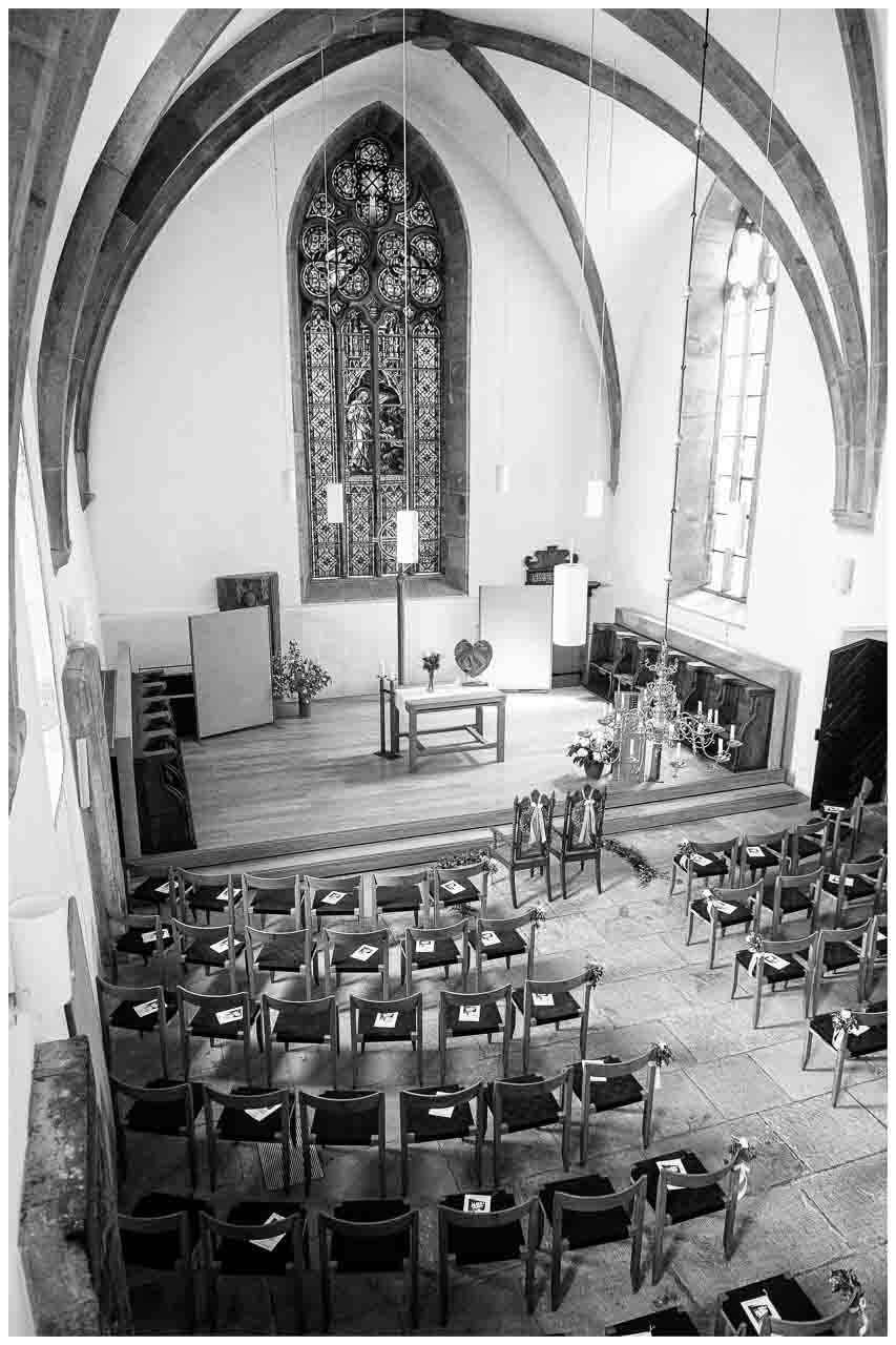 Feierliche Atmosphaere in der Kirche: Blick auf den Altarraum und die dekorierten Stuehle fuer die Hochzeitsgaeste, ein unvergesslicher Tag.