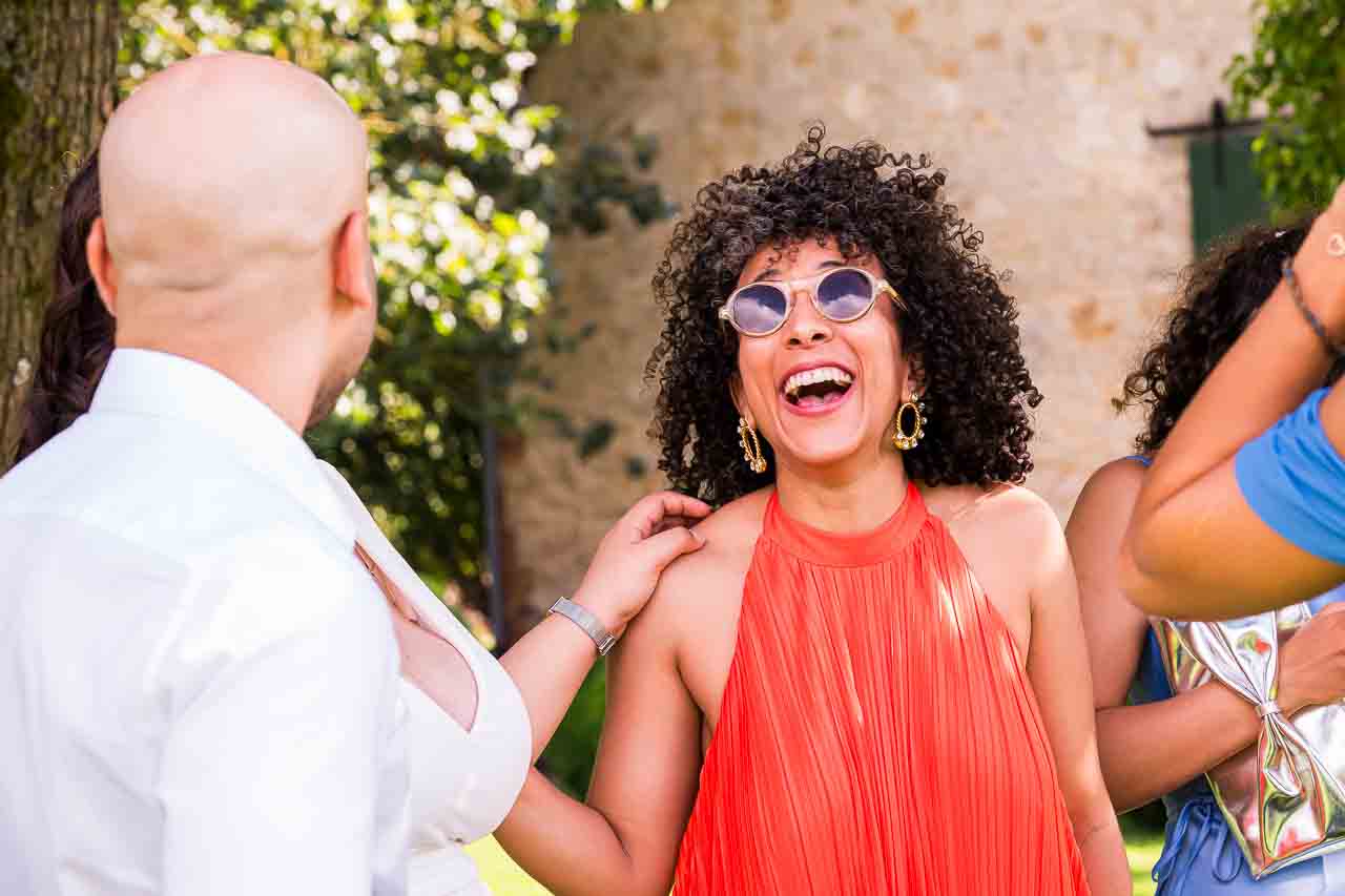 Fröhliche Frau in Orange lacht in Ockensen. Stilvolle Accessoires und lockere Atmosphäre. Weibliche Eleganz im Fokus.