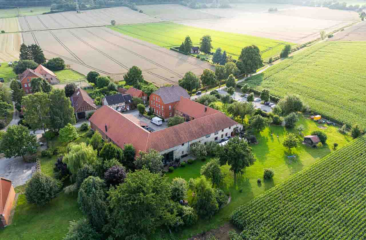 Luftaufnahme Mosterei Ockensen: Idyllische Hofanlage mit rotem Ziegeldach, umgeben von grünen Feldern. Ein Ort zum Verweilen und Genießen.