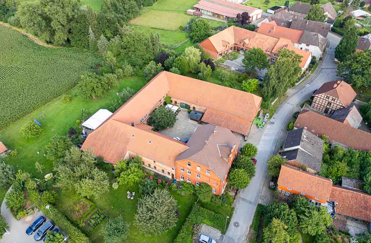 Luftaufnahme von Mosterei Ockensen: Idyllische Hofanlage mit roten Dächern, umgeben von sattem Grün. Ein Ort zum Verweilen und Genießen.