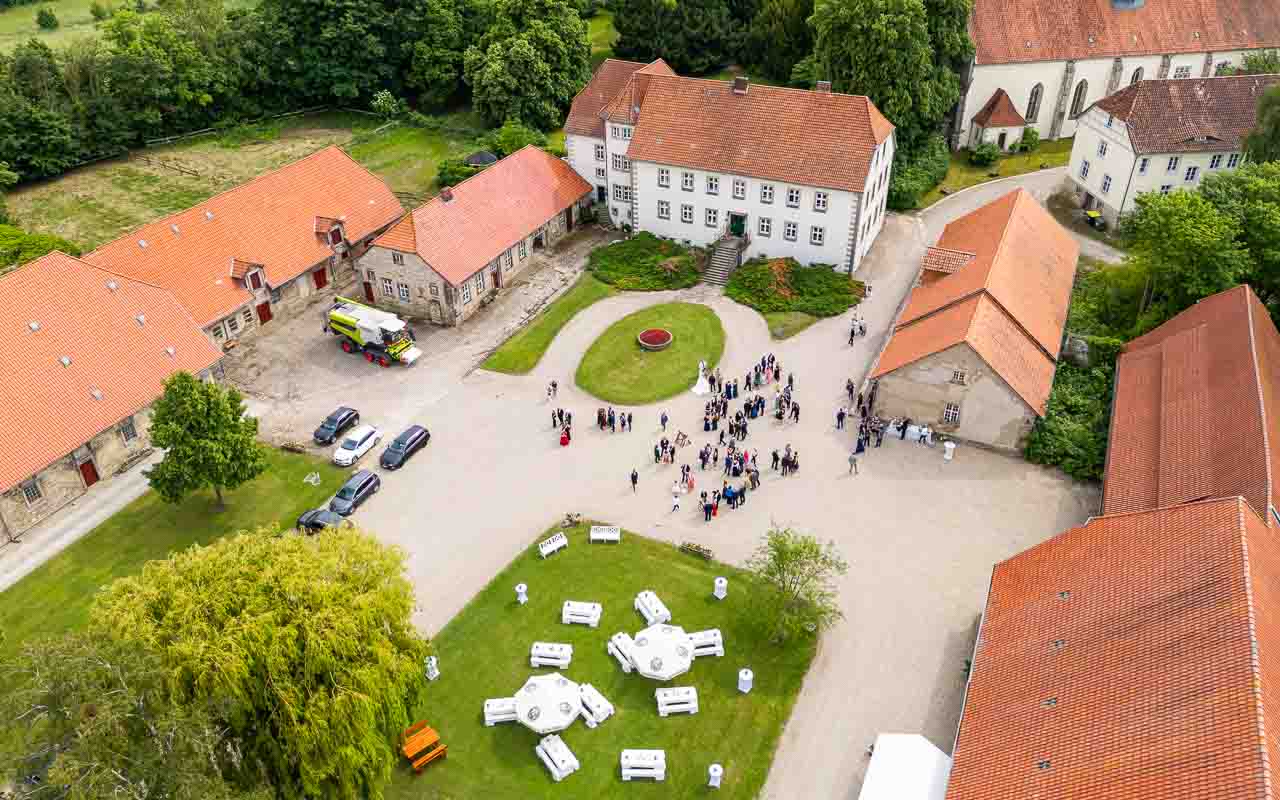 Luftaufnahme von Schloss Bredenbeck: Festliche Hochzeitsgesellschaft vor dem historischen Herrenhaus. Romantische Atmosphaere fuer den besonderen Tag.