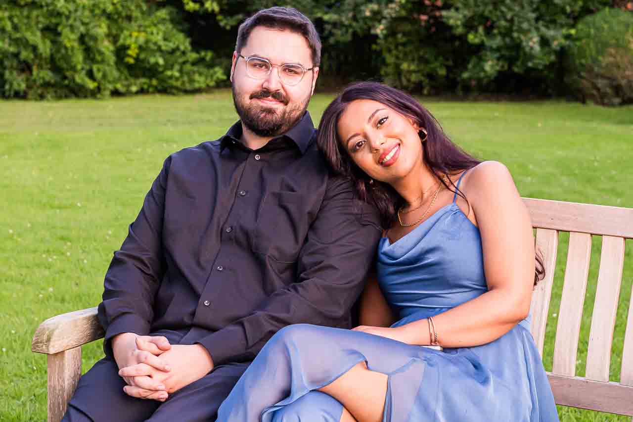 Liebe in Hannover: Ein stilvolles Paar genießt die Zweisamkeit auf einer Parkbank. Sie trägt ein elegantes, blaues Kleid mit zarten Details.