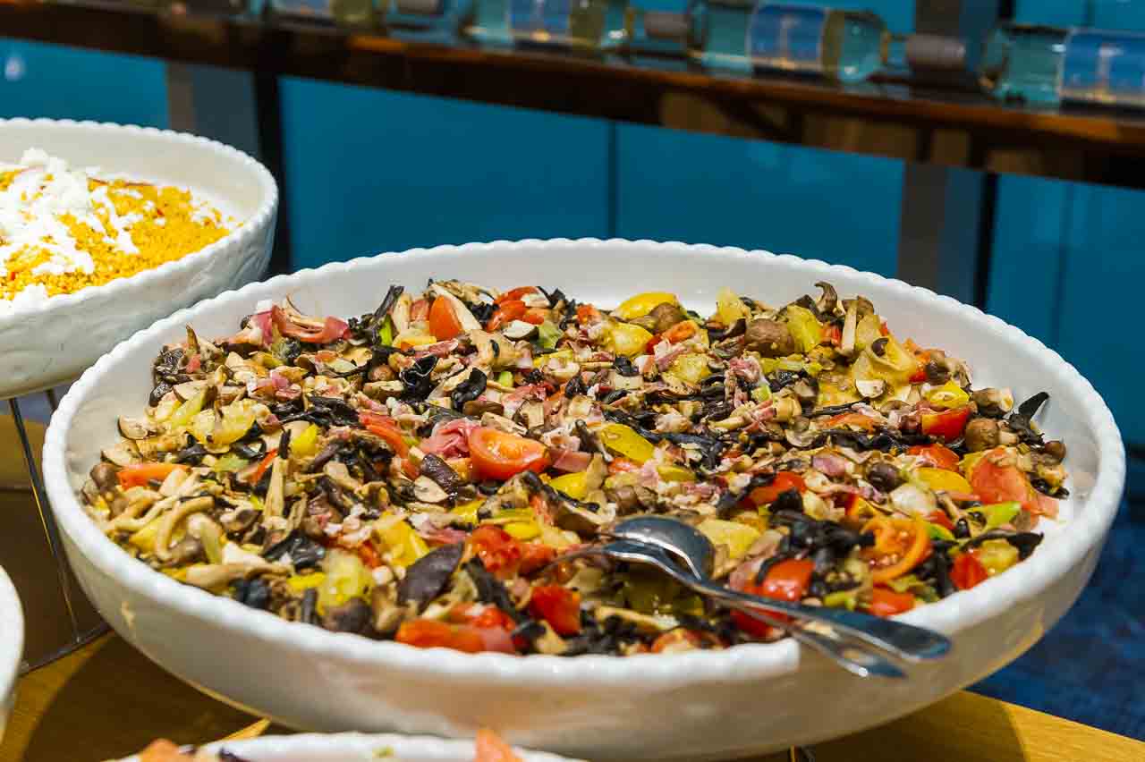 Appetitlicher Pilzsalat mit frischen Tomaten und Kraeutern in einer eleganten Schale. Ein Genuss fuer Feinschmecker, der zum Probieren einlaedt.