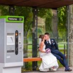 Romantisches Hochzeitsfoto in Hannover: Brautpaar küsst sich innig an einer Bahnshaltestelle der Uestra In Hannover Herrenhäuser Gärten. Sie im weißen Kleid, er im blauen Anzug.