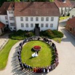 Hochzeitsgesellschaft umrahmt Brautpaar auf Schloss. Elegante Hochzeitslocation mit historischem Ambiente. Festliche Stimmung, unvergesslicher Tag.