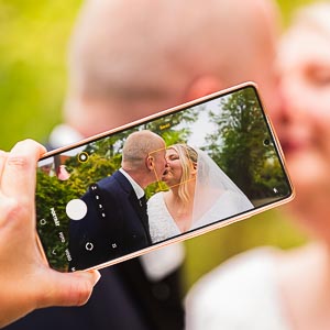 Handyfoto: Brautpaar-Kuss am Hochzeitstag. Romantische Hochzeitsmomente für die Ewigkeit festhalten. Liebe, Glück und unvergessliche Erinnerungen.
