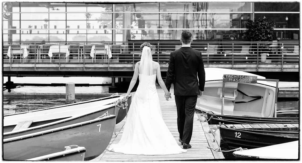 Ein Brautpaar geht Hand in Hand am Maschsee in Isernhagenentlang. Die Braut, in Weiss, fuehrt ihren Braeutigam zu einem schoenen gemeinsamen Leben.