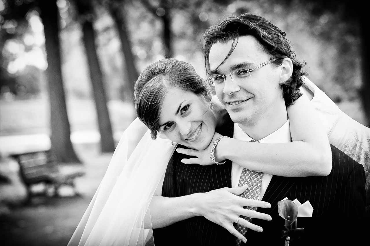 Ein elegantes Brautpaar umarmt sich innig im Park von Langenhagen. Die Braut, mit zartem Schleier, schmiegt sich an ihren Braeutigam – ein unvergesslicher Moment.